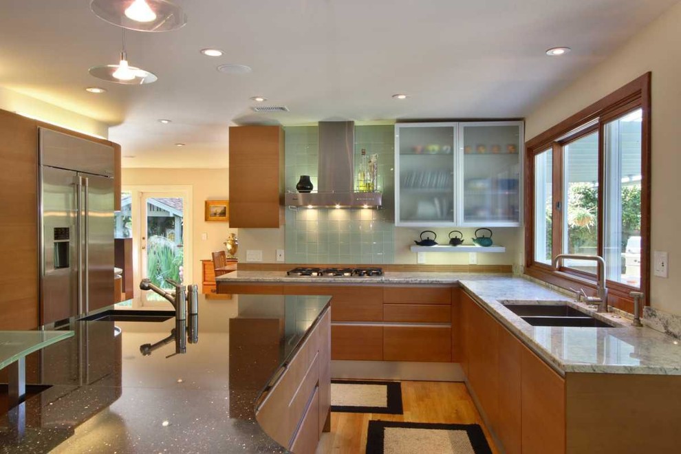 Large contemporary galley kitchen/diner in San Diego with a submerged sink, flat-panel cabinets, medium wood cabinets, granite worktops, green splashback, glass tiled splashback, stainless steel appliances, light hardwood flooring and an island.