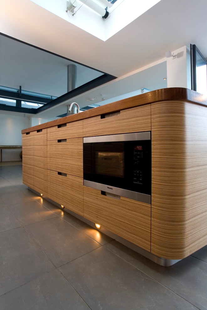 Réalisation d'une grande cuisine ouverte design en L et bois brun avec un placard à porte plane, un plan de travail en quartz modifié, une crédence verte et îlot.