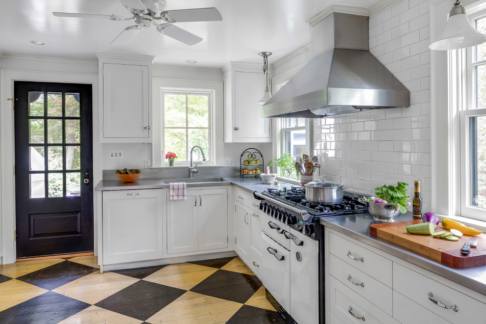Foto på ett mellanstort vintage l-kök, med en integrerad diskho, släta luckor, vita skåp, bänkskiva i rostfritt stål, vitt stänkskydd, stänkskydd i keramik, rostfria vitvaror och målat trägolv