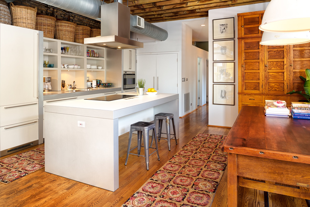 Imagen de cocina contemporánea abierta con armarios abiertos, electrodomésticos con paneles, suelo de madera en tonos medios y una isla