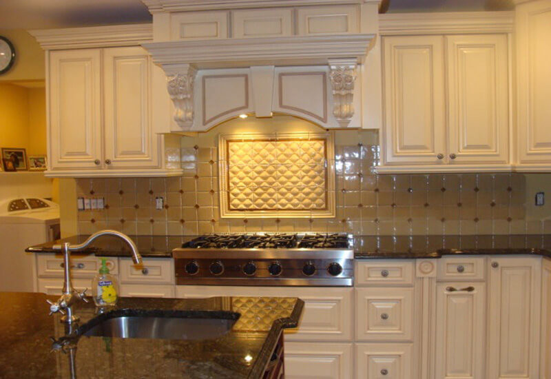Example of a mid-sized classic u-shaped light wood floor and brown floor enclosed kitchen design in New York with an undermount sink, raised-panel cabinets, white cabinets, granite countertops, beige backsplash, porcelain backsplash, stainless steel appliances and an island