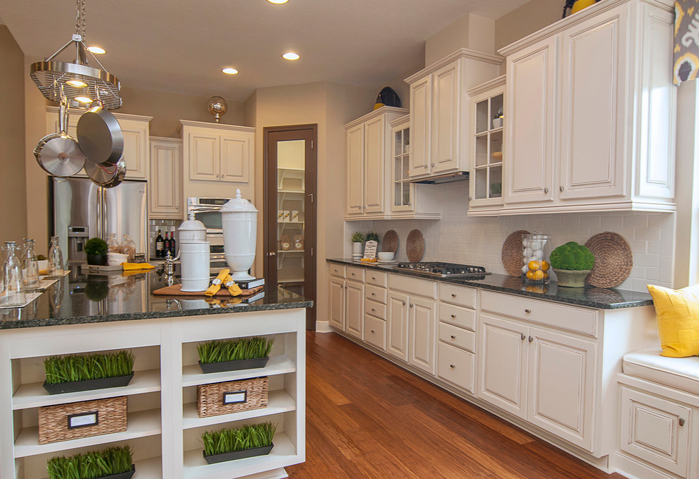 Foto de cocina clásica renovada de tamaño medio con puertas de armario blancas, encimera de cuarcita, salpicadero blanco, suelo marrón y encimeras grises