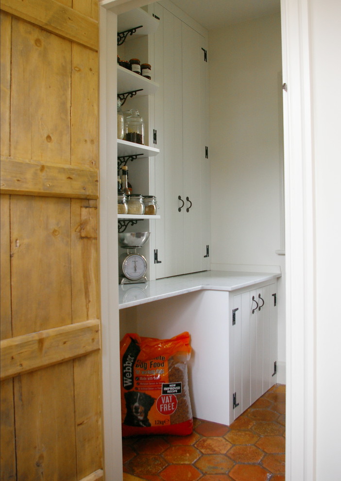 Diseño de cocina de estilo de casa de campo pequeña con despensa, armarios con rebordes decorativos, encimera de mármol y suelo de baldosas de terracota
