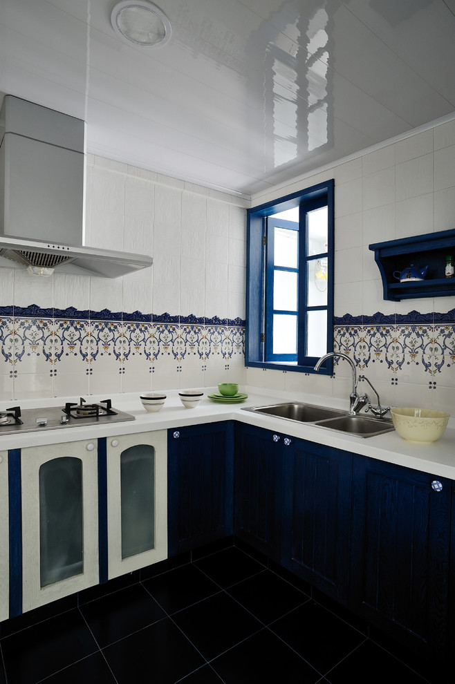 Aménagement d'une cuisine méditerranéenne avec un évier posé, des portes de placard bleues et une crédence multicolore.