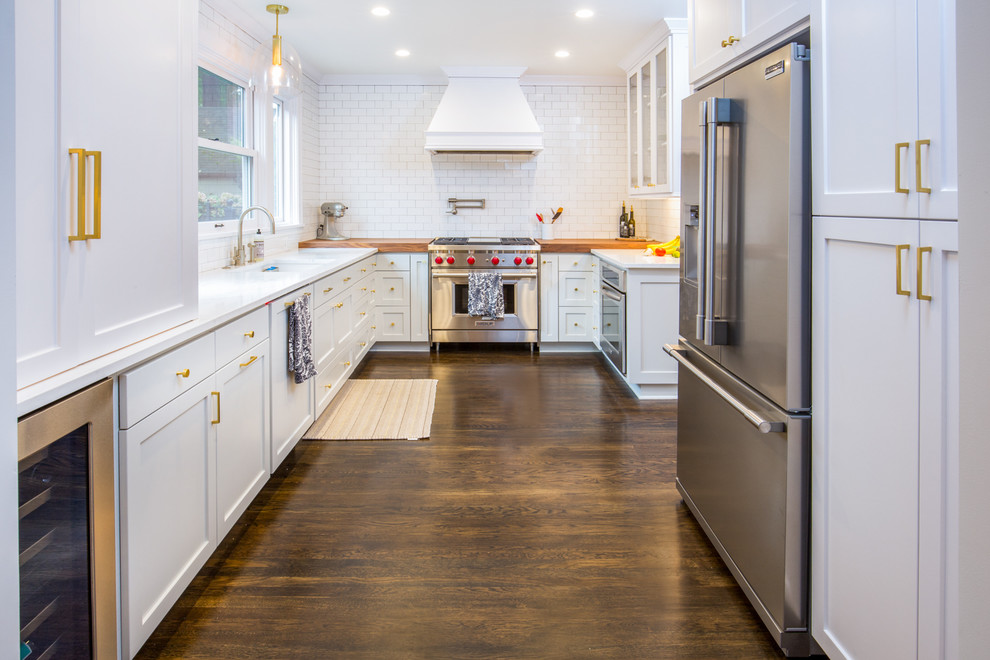 Inspiration for a large contemporary u-shaped dark wood floor and brown floor enclosed kitchen remodel in Portland with an undermount sink, shaker cabinets, white cabinets, solid surface countertops, white backsplash, subway tile backsplash, stainless steel appliances and no island