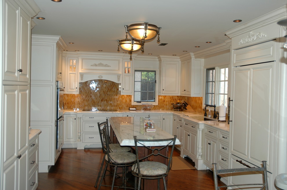 Exempel på ett mellanstort klassiskt kök, med en undermonterad diskho, luckor med upphöjd panel, vita skåp, marmorbänkskiva, beige stänkskydd, stänkskydd i keramik, integrerade vitvaror, mellanmörkt trägolv, en köksö och brunt golv