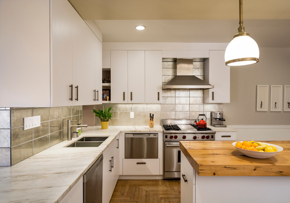 Exempel på ett klassiskt kök, med en dubbel diskho, släta luckor, vita skåp, träbänkskiva, stänkskydd med metallisk yta, stänkskydd i metallkakel, rostfria vitvaror, mellanmörkt trägolv och en köksö