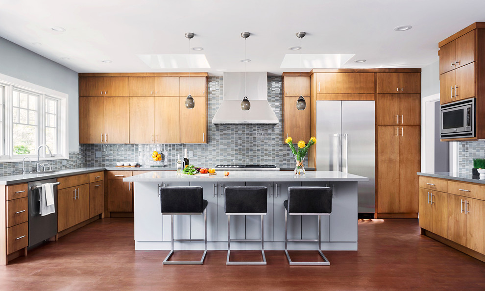 Moderne Küche in U-Form mit Küchenrückwand in Blau, Rückwand aus Glasfliesen, dunklem Holzboden, Kücheninsel, Unterbauwaschbecken, flächenbündigen Schrankfronten, hellbraunen Holzschränken und Küchengeräten aus Edelstahl in Boston