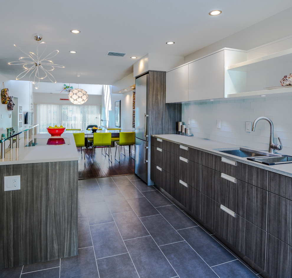 Design ideas for a contemporary open plan kitchen in Tampa with a submerged sink, dark wood cabinets, white splashback, metro tiled splashback and stainless steel appliances.