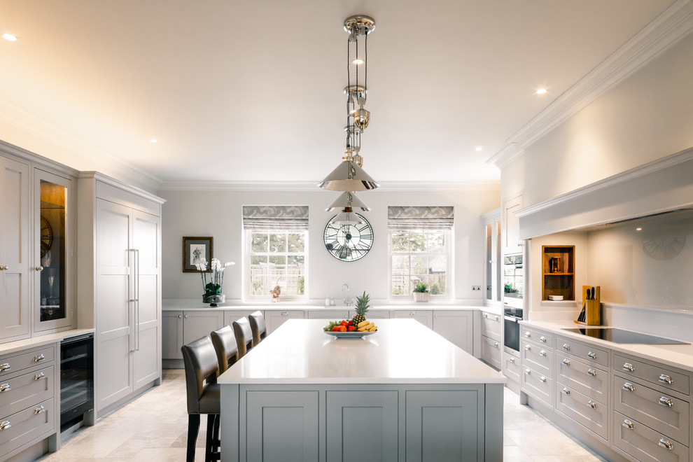 Immagine di un grande cucina con isola centrale chic con ante in stile shaker, ante grigie, top bianco, paraspruzzi grigio, paraspruzzi con lastra di vetro e pavimento bianco