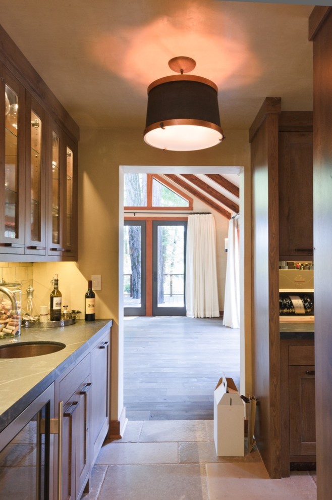 Foto på ett stort kök, med en undermonterad diskho, luckor med infälld panel, skåp i mellenmörkt trä, bänkskiva i kalksten, integrerade vitvaror och flera köksöar