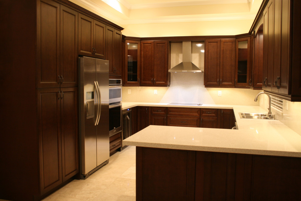 Exempel på ett modernt kök, med luckor med upphöjd panel, skåp i mörkt trä, bänkskiva i kvartsit, rostfria vitvaror och en halv köksö