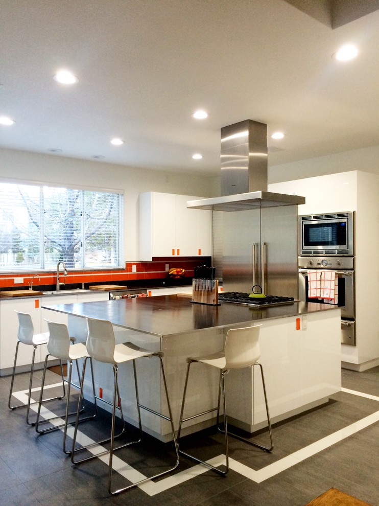 This is an example of a medium sized modern l-shaped kitchen/diner in Other with a submerged sink, flat-panel cabinets, white cabinets, stainless steel worktops, orange splashback, glass tiled splashback, stainless steel appliances, ceramic flooring and an island.