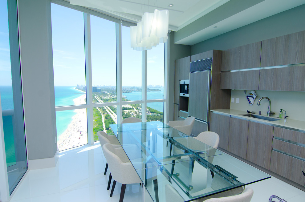 Einzeilige Moderne Wohnküche mit Unterbauwaschbecken, flächenbündigen Schrankfronten, hellbraunen Holzschränken und Elektrogeräten mit Frontblende in Miami