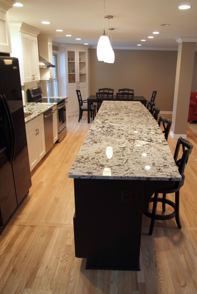 Example of a mid-sized transitional galley light wood floor eat-in kitchen design in Other with a single-bowl sink, shaker cabinets, white cabinets, granite countertops, stainless steel appliances and an island