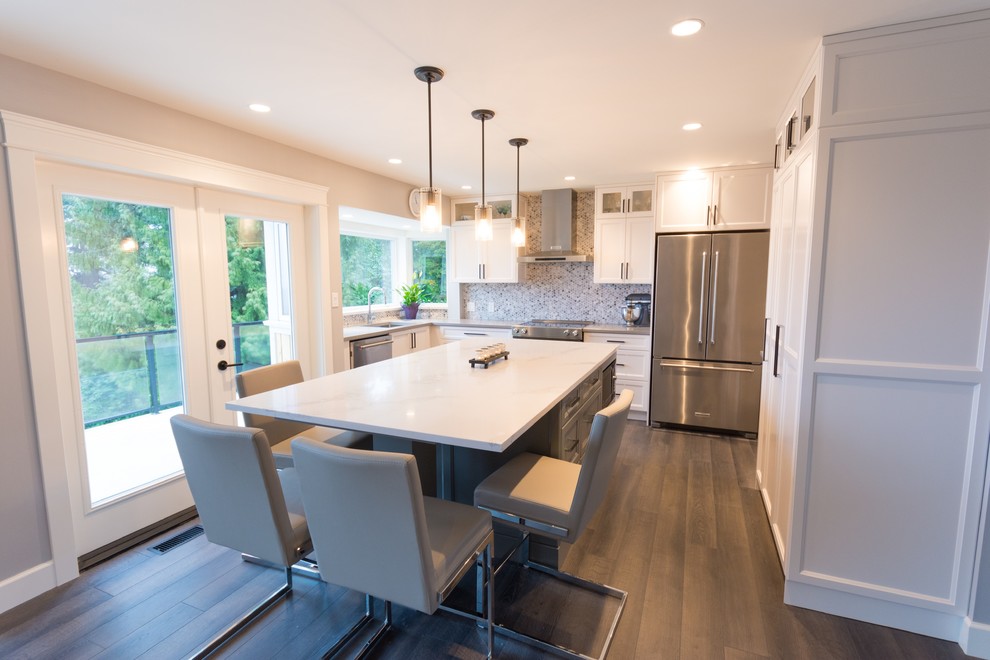 Photo of a modern l-shaped kitchen pantry in Vancouver with a submerged sink, recessed-panel cabinets, white cabinets, grey splashback, glass tiled splashback, stainless steel appliances, vinyl flooring, an island and brown floors.