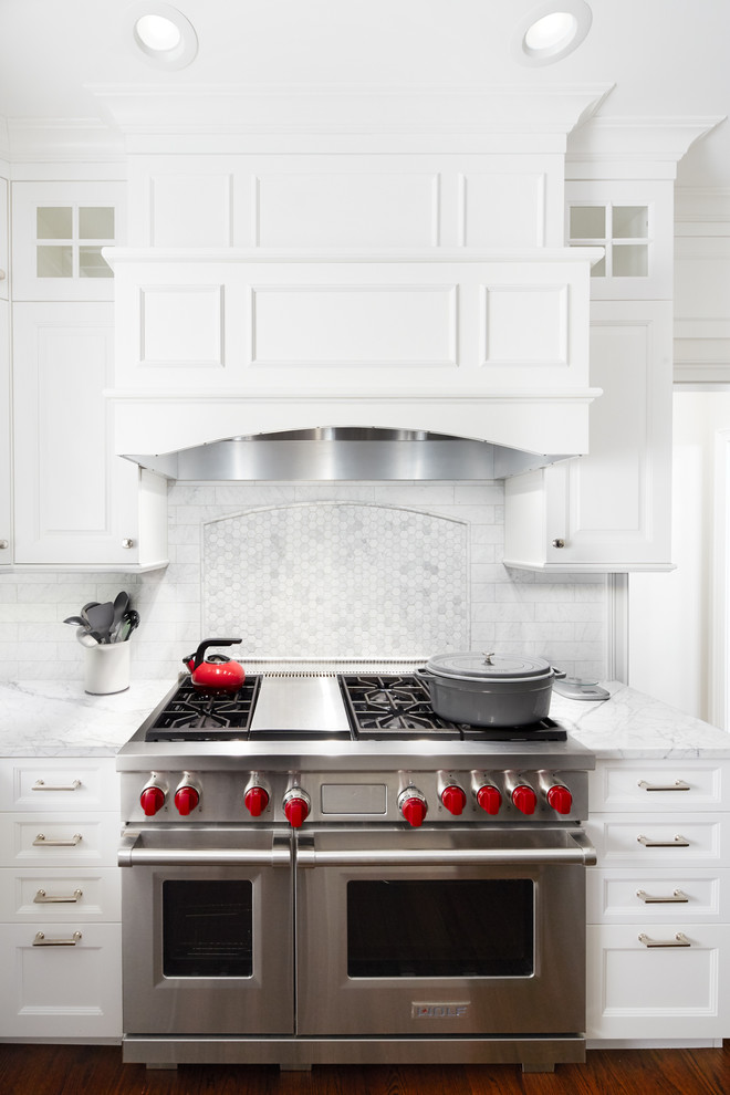 Ejemplo de cocina comedor clásica renovada de tamaño medio con puertas de armario blancas, encimera de mármol, salpicadero blanco, salpicadero con mosaicos de azulejos, electrodomésticos de acero inoxidable, suelo de madera oscura, una isla y armarios con paneles empotrados