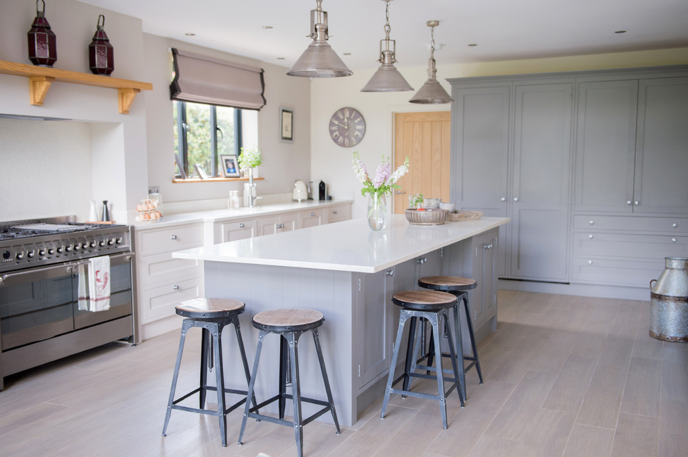 Design ideas for a medium sized country l-shaped kitchen in Cornwall with recessed-panel cabinets, grey cabinets, stainless steel appliances, light hardwood flooring, an island, beige floors and white worktops.