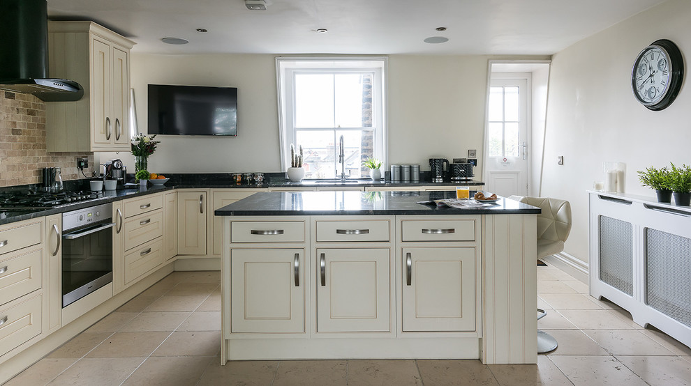 Bohemian l-shaped kitchen in London with a belfast sink, flat-panel cabinets, white cabinets, grey splashback, glass sheet splashback, stainless steel appliances and dark hardwood flooring.