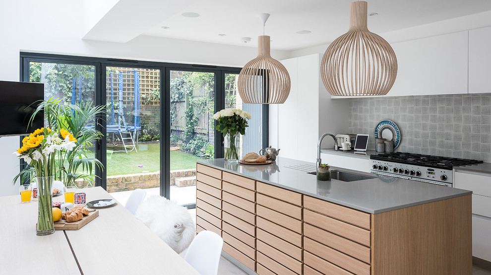 Scandi galley kitchen/diner in London with a submerged sink, flat-panel cabinets, white cabinets, grey splashback, stainless steel appliances, medium hardwood flooring and an island.