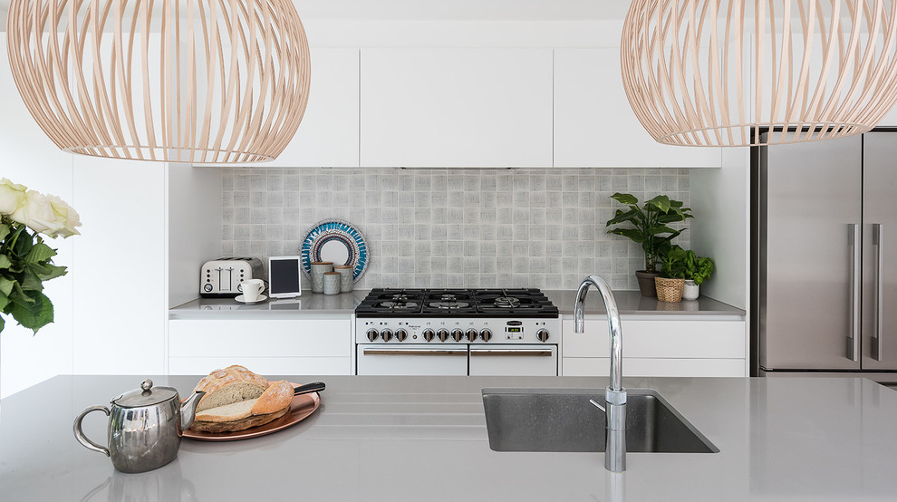 Eat-in kitchen - scandinavian galley medium tone wood floor eat-in kitchen idea in London with an undermount sink, flat-panel cabinets, white cabinets, gray backsplash, stainless steel appliances and an island