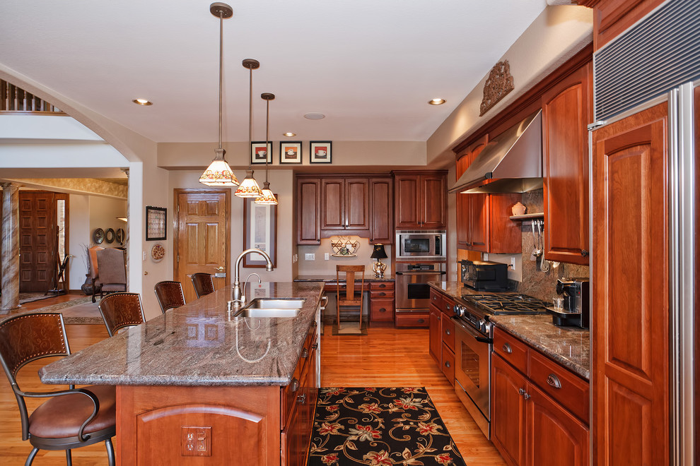 Elegant kitchen photo in Denver with granite countertops and paneled appliances
