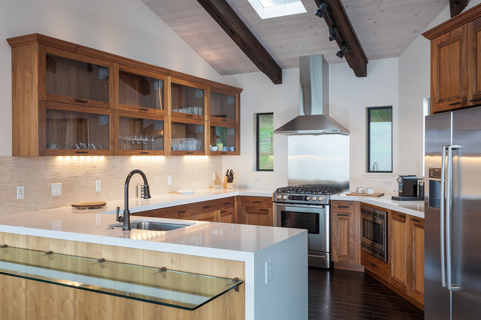 Moderne Küche mit Unterbauwaschbecken, Glasfronten, hellbraunen Holzschränken, Küchengeräten aus Edelstahl, dunklem Holzboden und Halbinsel in Orange County