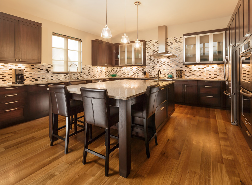Inspiration for a large contemporary u-shaped medium tone wood floor kitchen remodel in Denver with glass-front cabinets, dark wood cabinets, granite countertops, brown backsplash, mosaic tile backsplash, stainless steel appliances and an island