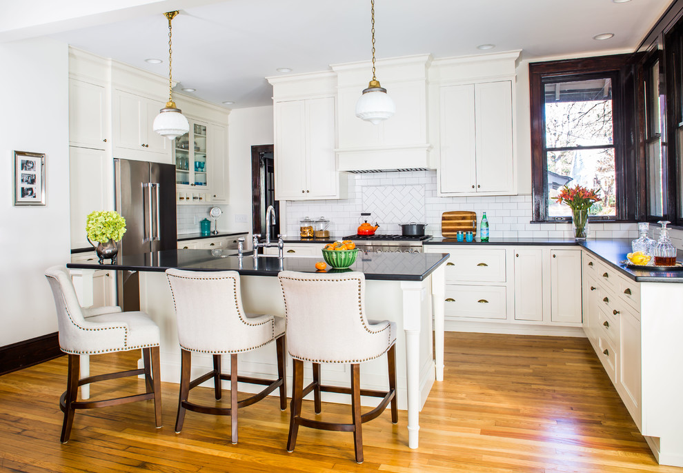 Große Klassische Küche in L-Form mit Küchenrückwand in Weiß, Rückwand aus Metrofliesen, Küchengeräten aus Edelstahl, Kücheninsel, Schrankfronten im Shaker-Stil und braunem Holzboden in Atlanta
