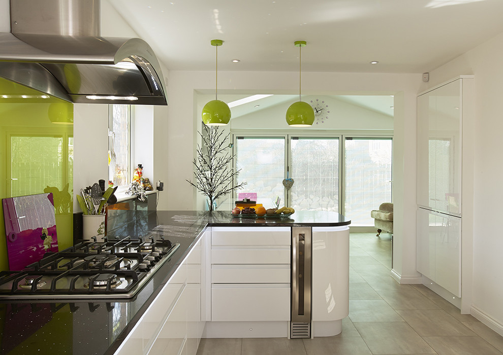 Inspiration for a large contemporary galley kitchen/diner in Other with flat-panel cabinets, white cabinets, green splashback, glass sheet splashback, ceramic flooring, a breakfast bar, white appliances and a submerged sink.