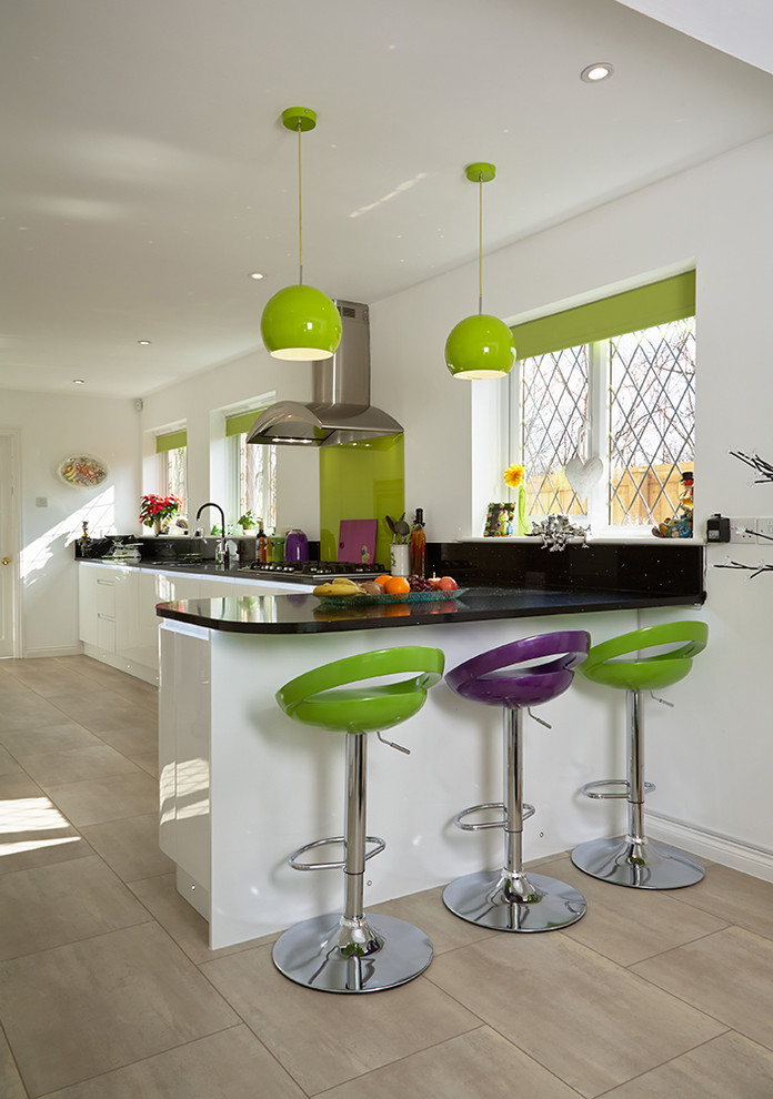 На фото: большая параллельная кухня в современном стиле с обеденным столом, плоскими фасадами, белыми фасадами, зеленым фартуком, фартуком из стекла, светлым паркетным полом и полуостровом