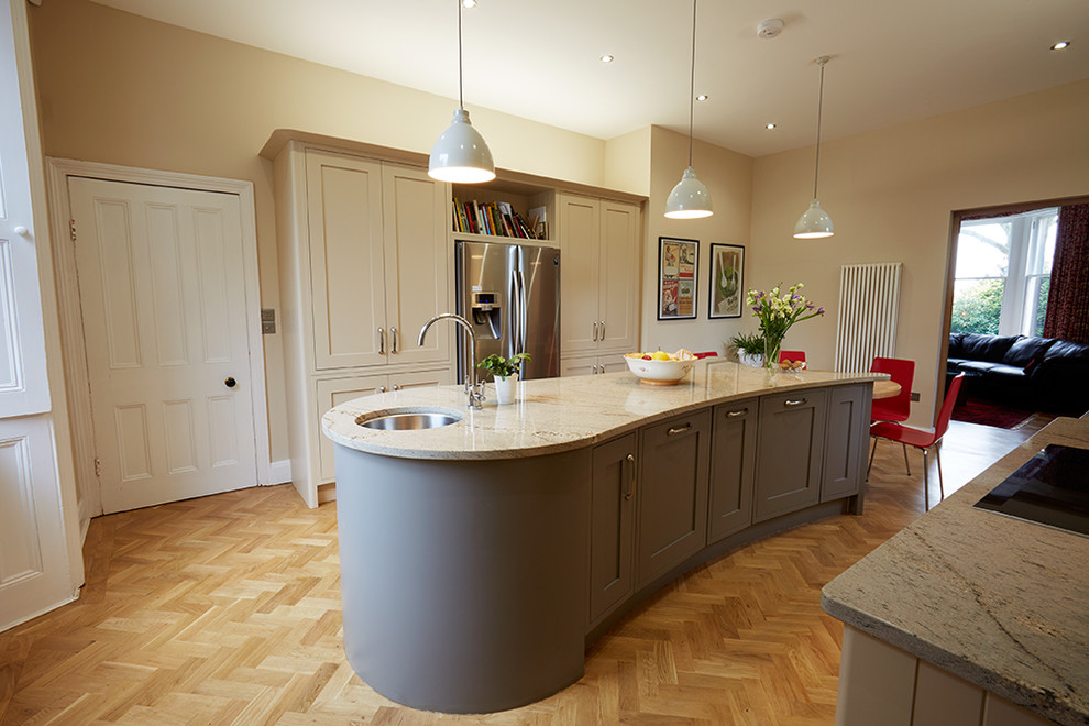 Example of a large classic galley light wood floor eat-in kitchen design in Other with an undermount sink, recessed-panel cabinets, gray cabinets, granite countertops, stainless steel appliances and an island