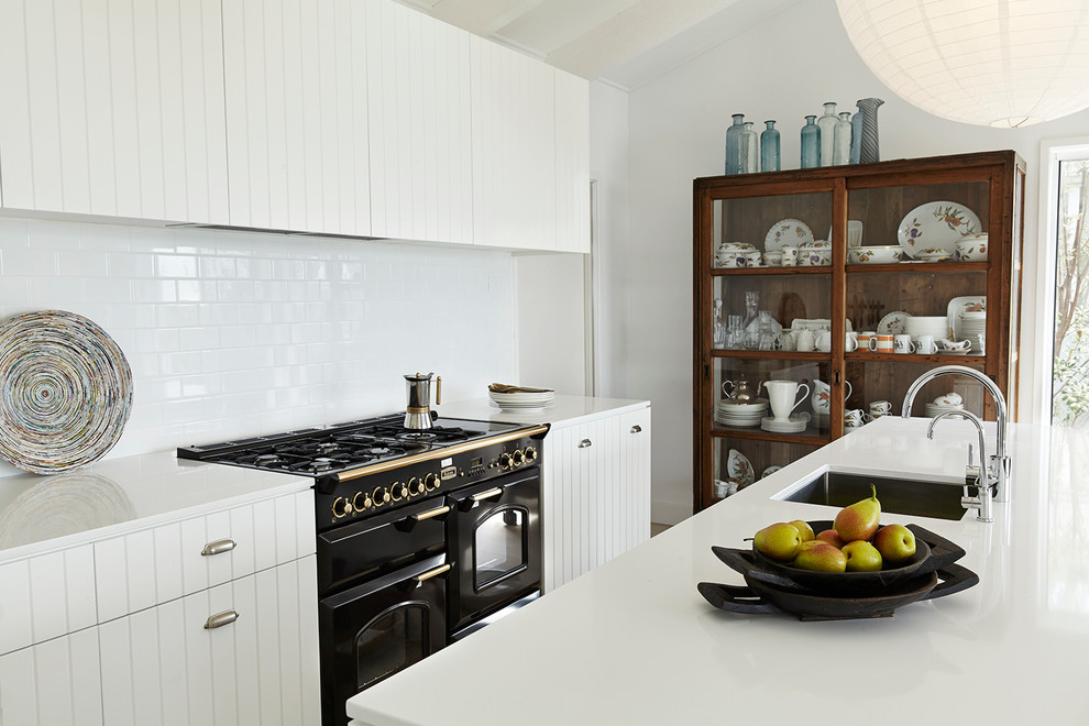 ロンドンにあるコンテンポラリースタイルのおしゃれなキッチン (アンダーカウンターシンク、白いキャビネット、白いキッチンパネル、サブウェイタイルのキッチンパネル、黒い調理設備) の写真