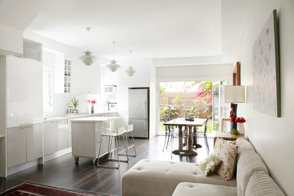 Idée de décoration pour une cuisine ouverte nordique en L avec un placard à porte plane, des portes de placard blanches, une crédence blanche, un électroménager en acier inoxydable, parquet foncé et îlot.