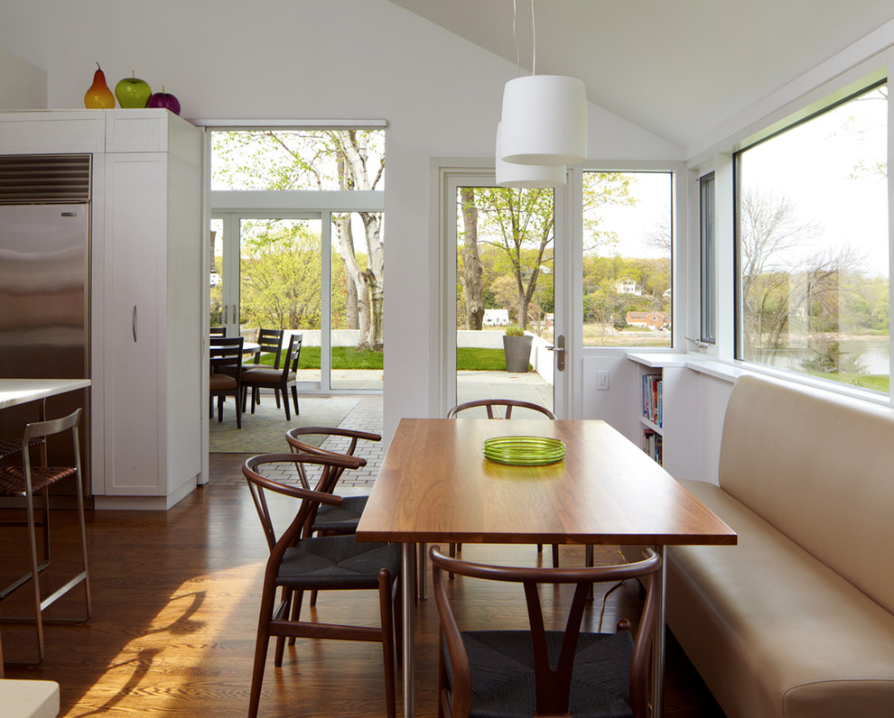 Mittelgroße Moderne Wohnküche mit Schrankfronten im Shaker-Stil, weißen Schränken, Küchengeräten aus Edelstahl, braunem Holzboden und Kücheninsel in New York