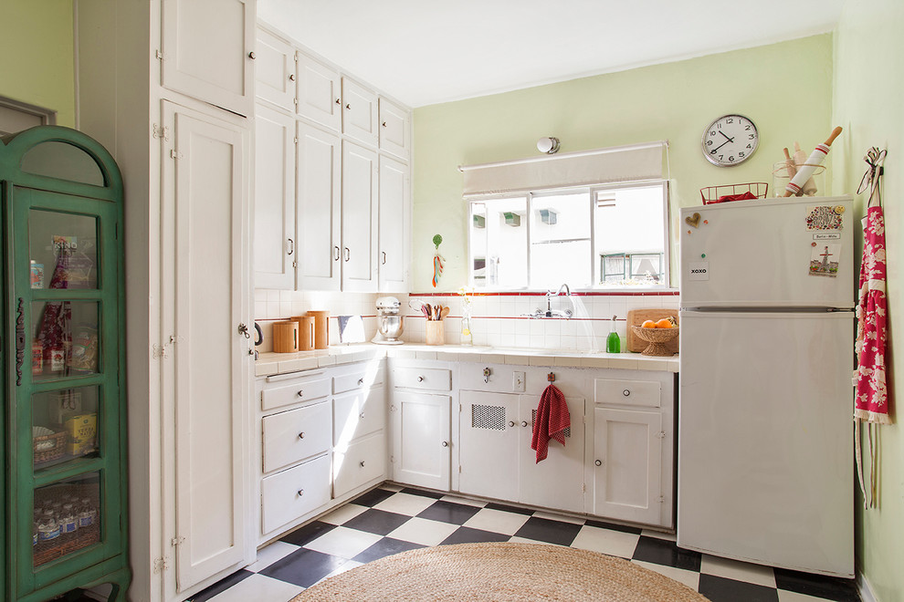 Example of a classic l-shaped kitchen design in Bilbao with white cabinets, tile countertops, white backsplash, ceramic backsplash and white appliances