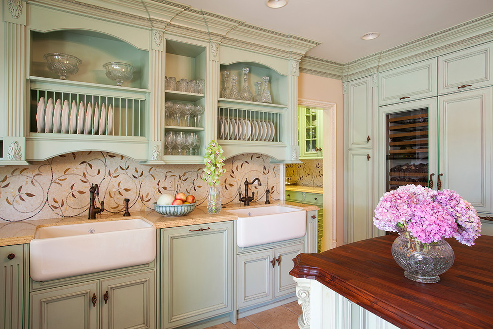Inspiration for a timeless kitchen remodel in Los Angeles with a farmhouse sink, recessed-panel cabinets, green cabinets, beige backsplash, mosaic tile backsplash, paneled appliances and an island