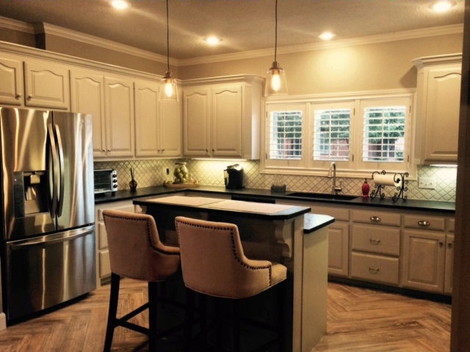 Example of a mid-sized minimalist u-shaped light wood floor eat-in kitchen design in Austin with an undermount sink, raised-panel cabinets, white cabinets, limestone countertops, white backsplash, ceramic backsplash, stainless steel appliances and an island