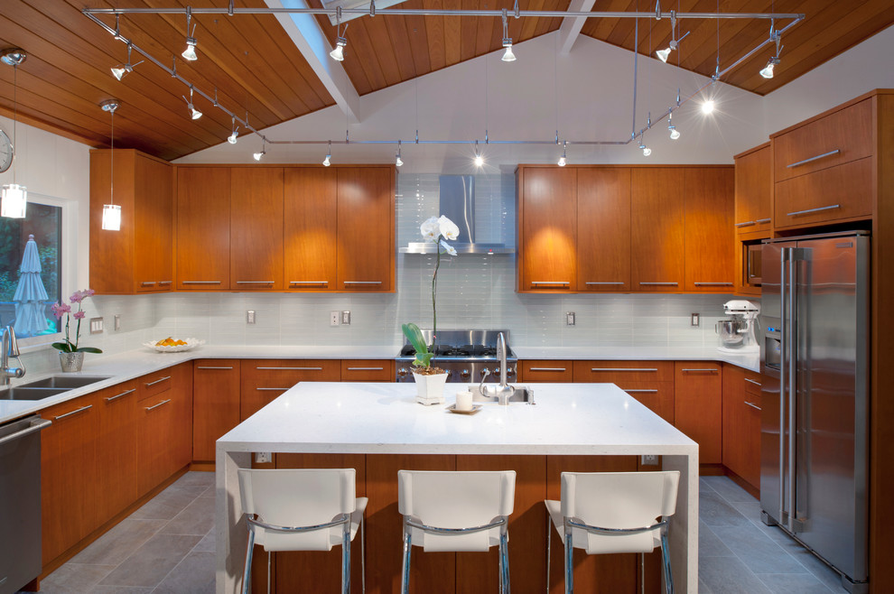 Moderne Küche in U-Form mit Rückwand aus Glasfliesen, Küchenrückwand in Weiß, flächenbündigen Schrankfronten, hellbraunen Holzschränken, Doppelwaschbecken und Küchengeräten aus Edelstahl in Vancouver