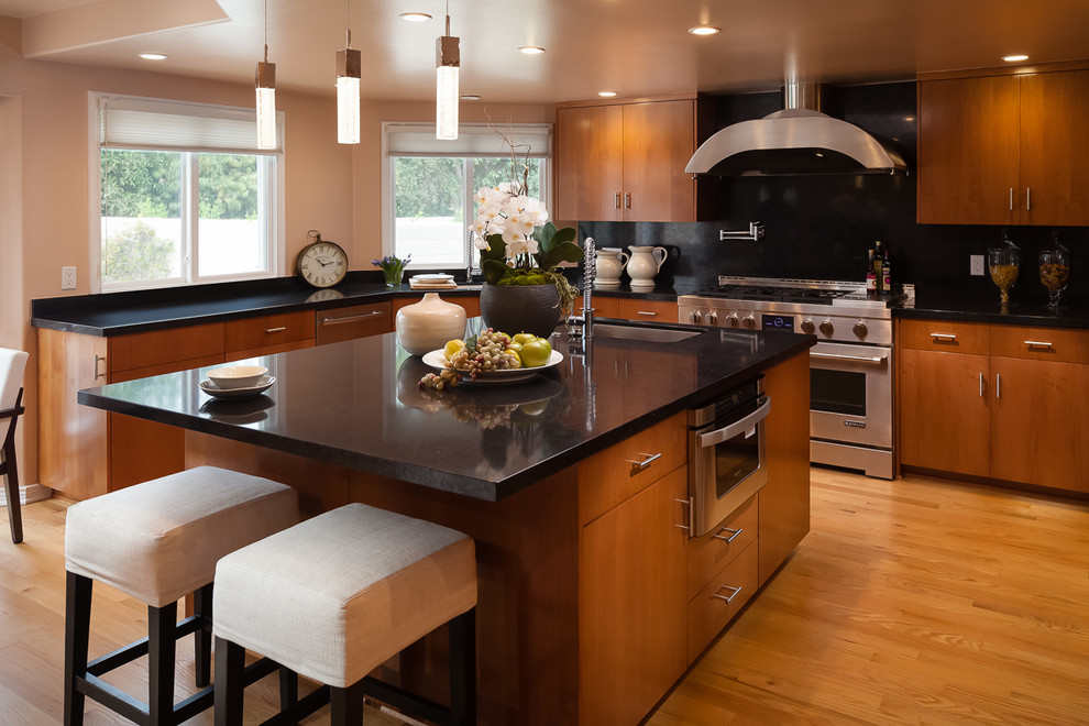 Eat-in kitchen - large modern u-shaped light wood floor eat-in kitchen idea in Los Angeles with flat-panel cabinets, medium tone wood cabinets, onyx countertops, black backsplash, ceramic backsplash, stainless steel appliances and an island