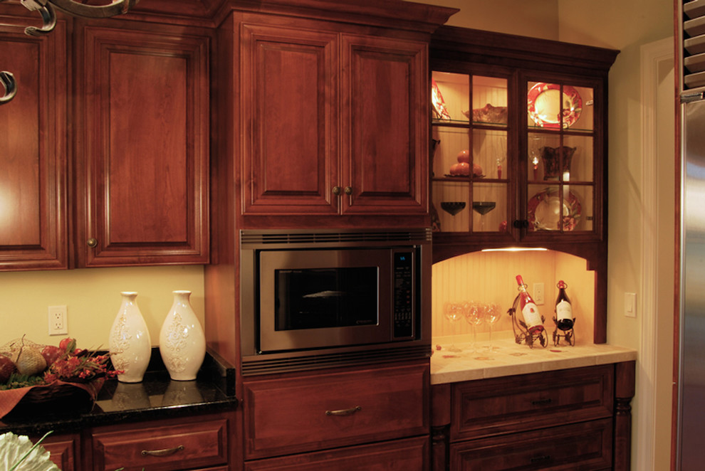 Cette photo montre une cuisine chic en bois brun avec un placard à porte affleurante et un électroménager en acier inoxydable.