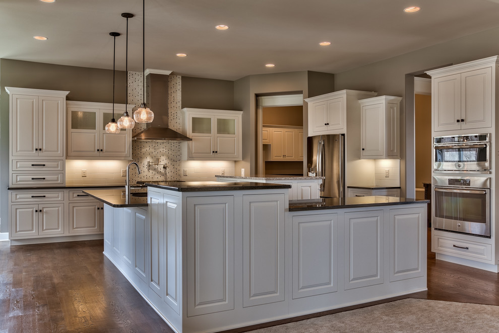 Kitchen - modern l-shaped dark wood floor kitchen idea in Omaha with a double-bowl sink, raised-panel cabinets, white cabinets, granite countertops, stainless steel appliances and two islands