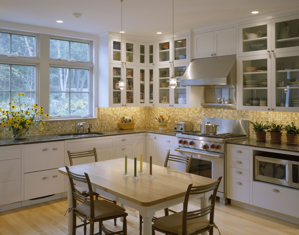 Modelo de cocina contemporánea con salpicadero con mosaicos de azulejos, salpicadero marrón, puertas de armario blancas, armarios tipo vitrina, fregadero bajoencimera y electrodomésticos de acero inoxidable