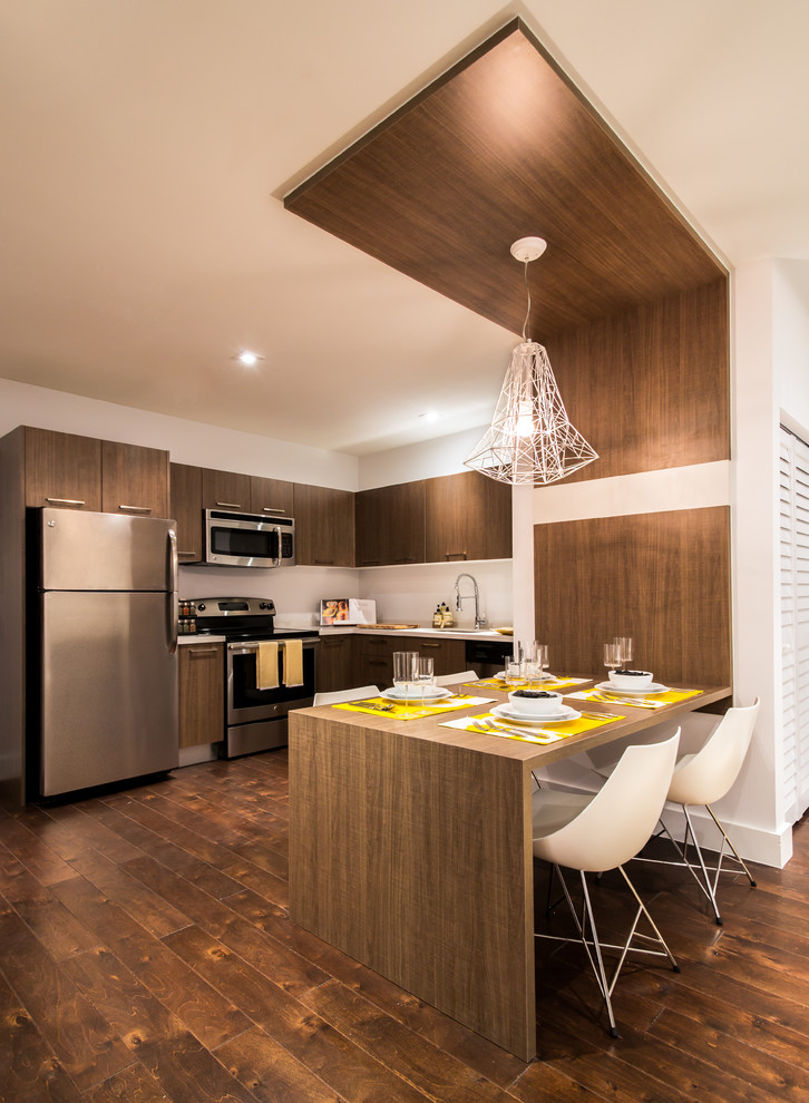 Moderne Wohnküche mit flächenbündigen Schrankfronten, dunklen Holzschränken, Küchenrückwand in Weiß, Küchengeräten aus Edelstahl und dunklem Holzboden in Miami