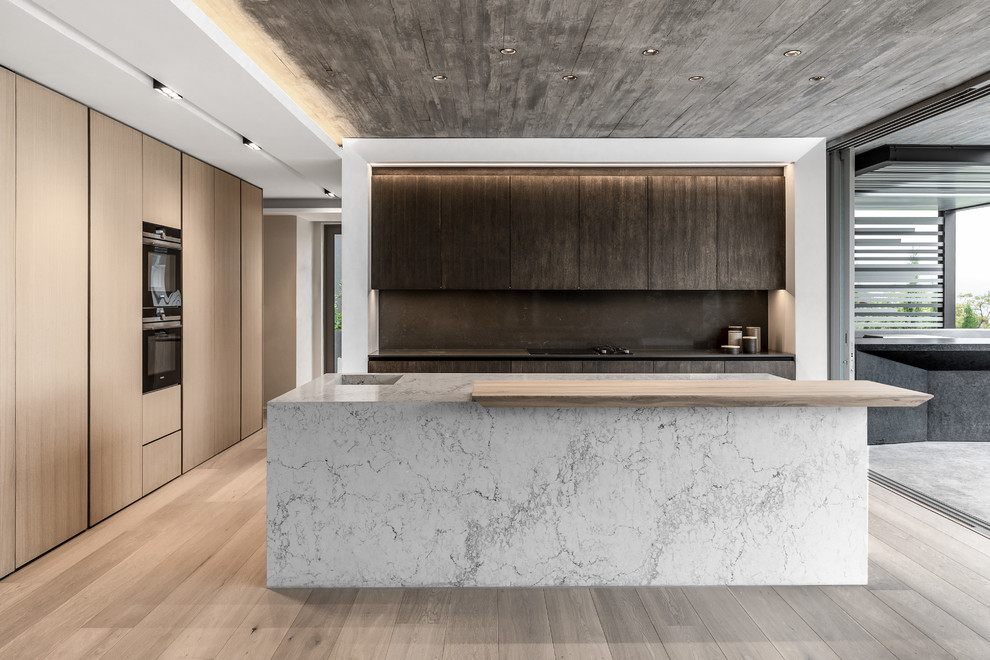Foto di una cucina minimal con lavello integrato, ante lisce, ante in legno chiaro, paraspruzzi grigio, parquet chiaro, pavimento grigio e top bianco