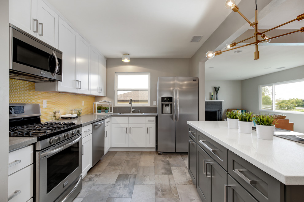 Example of a small minimalist l-shaped porcelain tile open concept kitchen design in San Diego with a drop-in sink, shaker cabinets, white cabinets, quartz countertops, yellow backsplash, mosaic tile backsplash, stainless steel appliances and an island