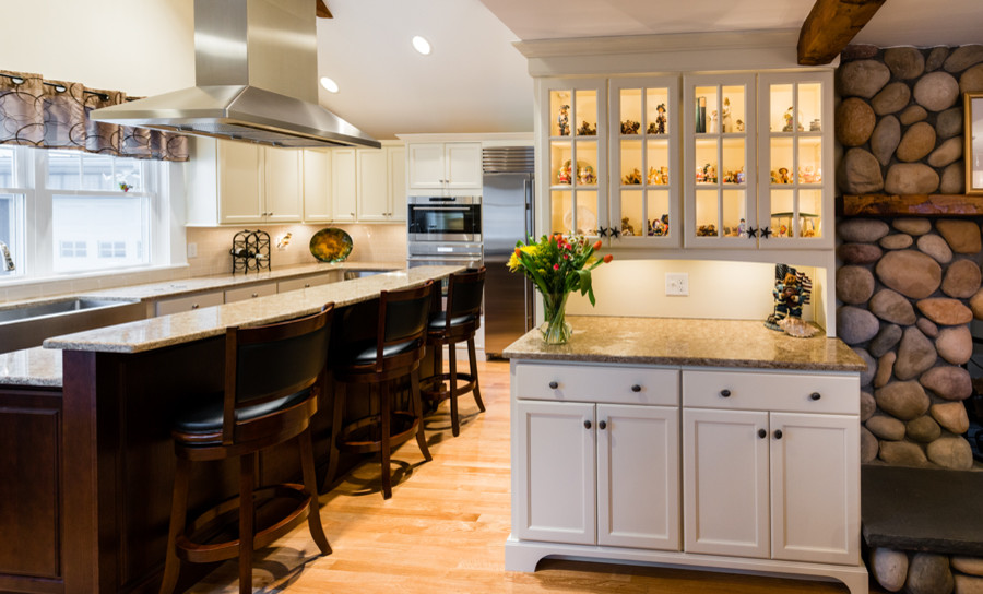 Inspiration for a mid-sized transitional l-shaped light wood floor kitchen remodel in Boston with a farmhouse sink, recessed-panel cabinets, white cabinets, quartz countertops, beige backsplash, subway tile backsplash and stainless steel appliances