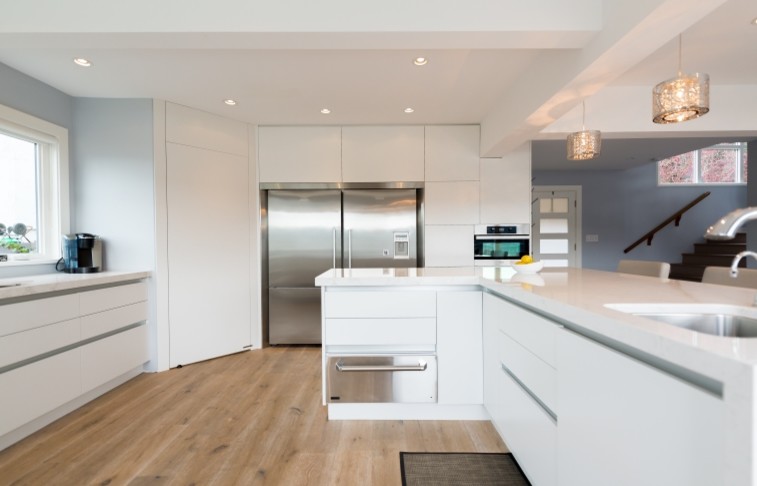 Photo of a large contemporary kitchen/diner in Vancouver with a submerged sink, flat-panel cabinets, white cabinets, engineered stone countertops, stainless steel appliances, light hardwood flooring and an island.