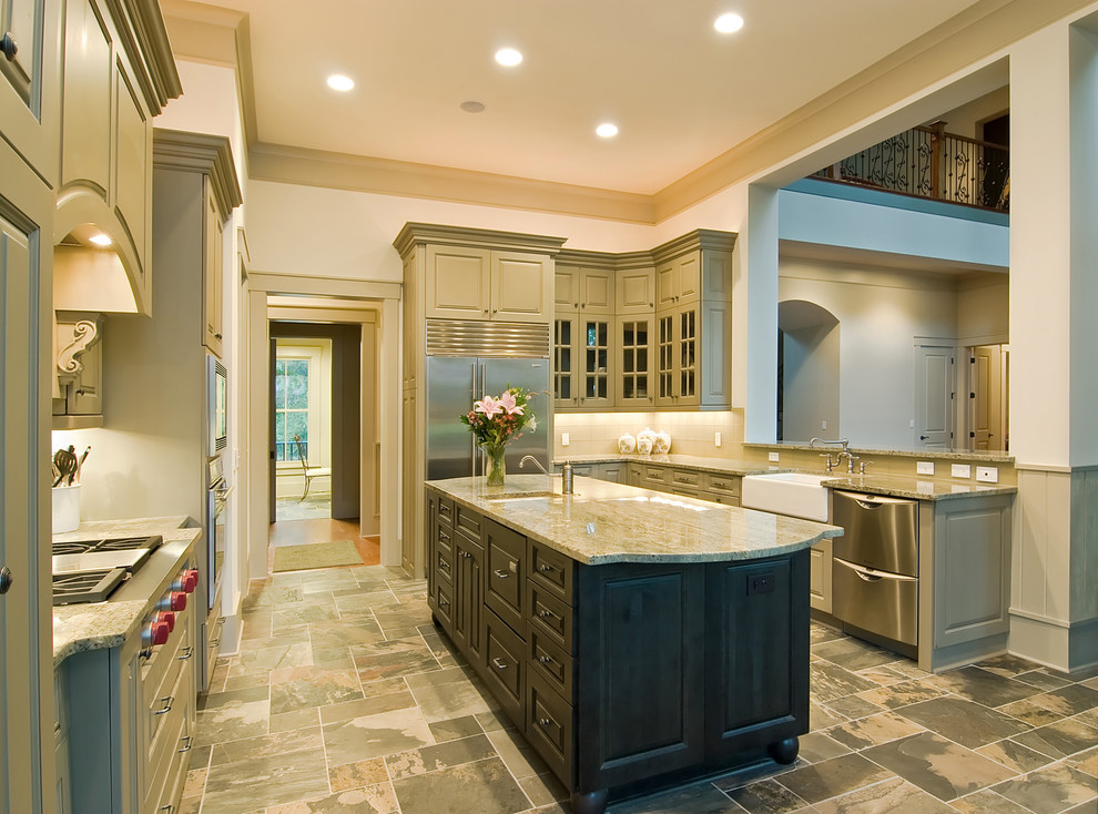 Example of a large classic u-shaped slate floor open concept kitchen design in San Francisco with a farmhouse sink, raised-panel cabinets, green cabinets, granite countertops, beige backsplash, porcelain backsplash, stainless steel appliances and an island