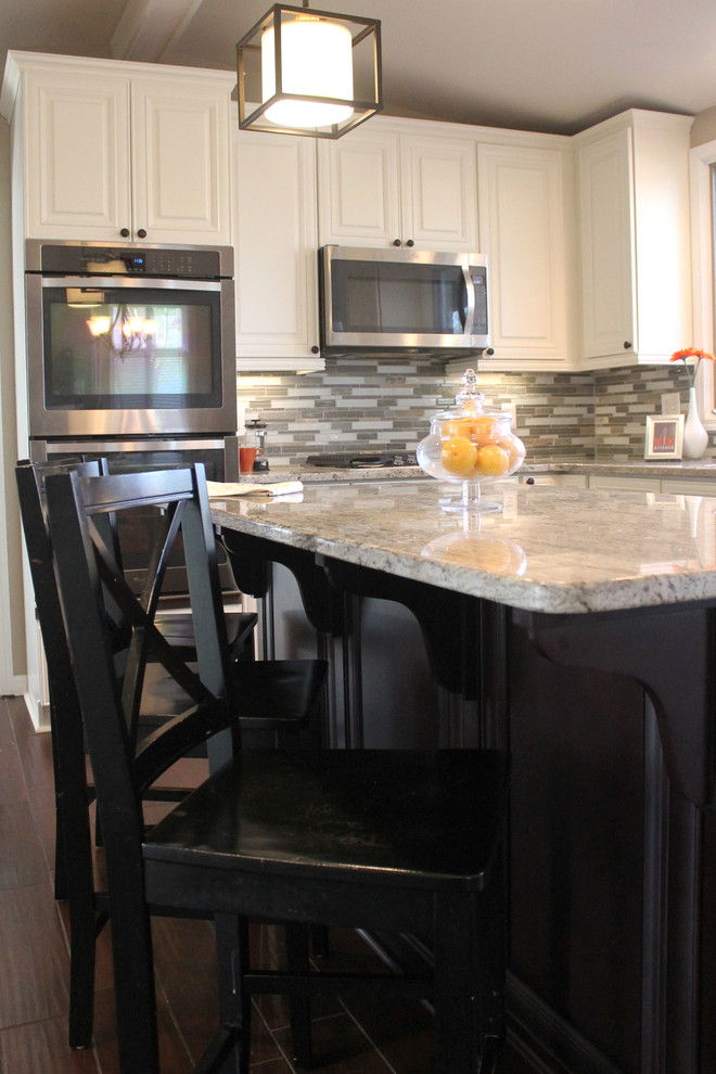 Example of a mid-sized transitional u-shaped dark wood floor eat-in kitchen design in Detroit with an undermount sink, raised-panel cabinets, white cabinets, granite countertops, beige backsplash, glass tile backsplash, stainless steel appliances and an island